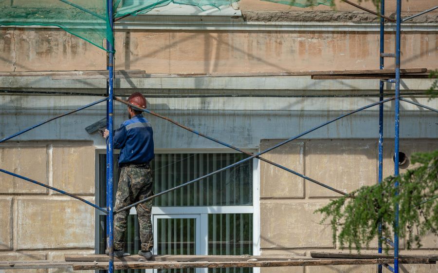 Técnico en andamio colgante limpiando un muro cortina